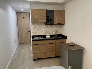 A compact kitchen with wooden cabinets, a marble backsplash, and a black countertop.