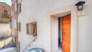 A narrow street with a building featuring a wooden door, a small window with shutters, and a wall-mounted light fixture. - Capu D'ortu - PIANA - Gîte (PIANA)