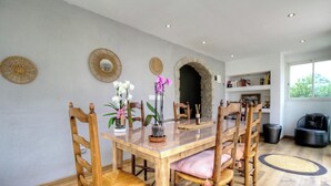 Un coin repas avec une table en bois, des chaises et deux orchidées en pot.