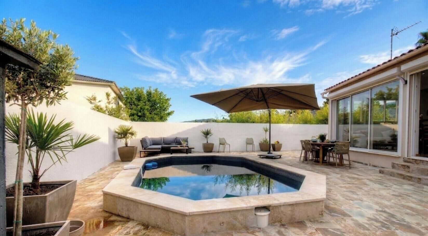 A swimming pool with a hot tub, outdoor furniture, and a patio area.