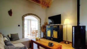 Un salon comprenant un canapé, une table basse en bois, un téléviseur, un meuble et une lampe.
