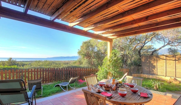 An outdoor patio with a wooden pergola, a round table set for dining, and a view of the landscape. - Le 692 - PROPRIANO - Gîte (PROPRIANO)