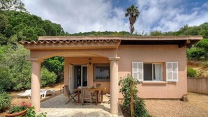A single-story house with a patio, a covered outdoor seating area, and a view of a hill. - 10676 - SAINTE LUCIE DE PORTO VECCHIO (SAINTE LUCIE DE PORTO VECCHIO)