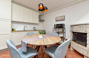Eine moderne Küche mit weißen Schränken, einem runden Holztisch und blauen Stühlen.