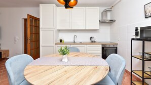 A modern kitchen with white cabinets, a round wooden table, and a two-person seating arrangement. - Apartment 2439/240919 (Istria - Stinjan), 1000m from the beach (Stinjan)