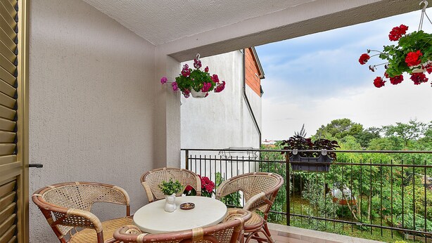 A balcony with wicker chairs, a round table, and hanging flower baskets. - Apartment 2439/240919 (Istria - Stinjan), 1000m from the beach (Stinjan)