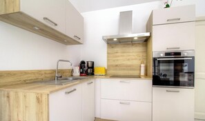 A modern kitchen with a wooden countertop, stainless steel appliances, and white cabinetry. - Casa Stella Marina - SAINT FLORENT (SAINT FLORENT)