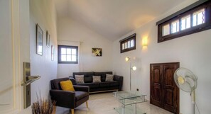 A living room with a sofa, armchair, glass coffee table, and a fan. - Casa Stella Marina - SAINT FLORENT (SAINT FLORENT)