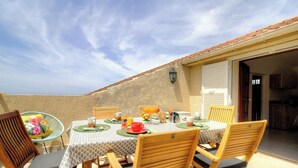 A balcony with a table set for breakfast, chairs, and a view of the sea. - Casa Stella Marina - SAINT FLORENT (SAINT FLORENT)