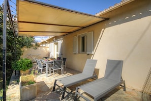 A covered patio with a table and chairs, two lounge chairs, and a potted plant. - Alimea - PRUNELLI DI FIUM'ORBO (PRUNELLI DI FIUM'ORBO)