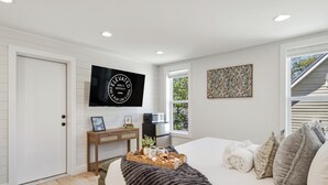 Quarto com cama, televisão, escrivaninha e janela.