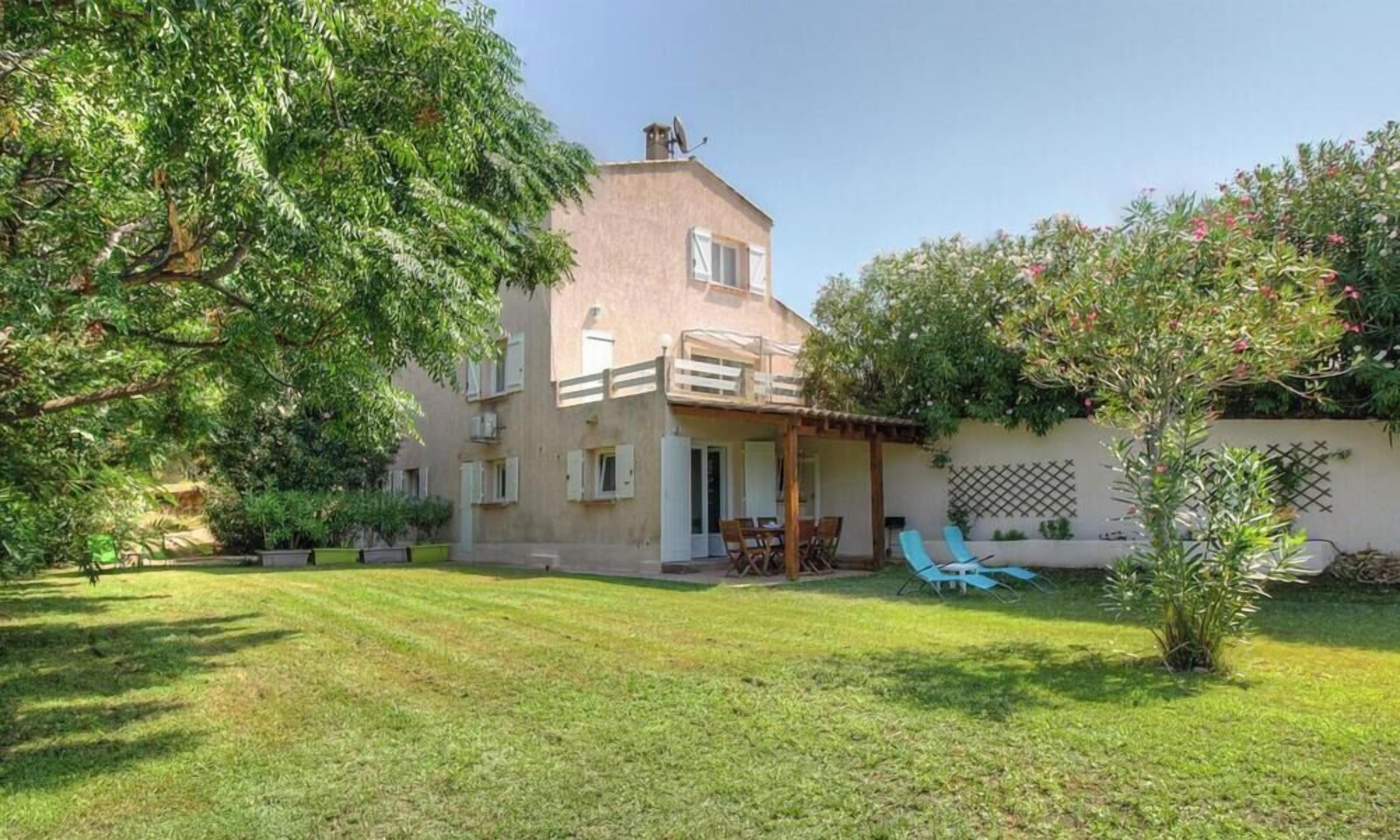 Una casa de dos pisos con un patio, césped y un árbol.
