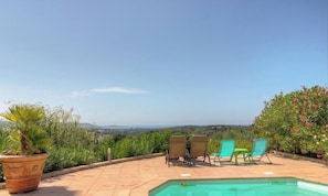 Ein Poolbereich mit Landschaftsblick, zwei Liegestühle und ein Blumentopf.