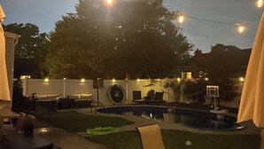 Ein Außenbereich mit Pool, Liegestühlen und Lichterketten.