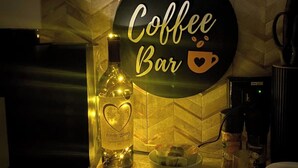 Eine Küchenarbeitsplatte mit einer Kaffeebar-Beschilderung, einer Flasche Wodka mit Monogramm, einer Kaffeemaschine und einer Schüssel mit Snacks.