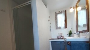 Een badkamer met een douche, een wastafel en een spiegel.