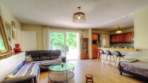 A living room with a sofa, a glass coffee table, and a dining area with a kitchen in the background. - Le 55742 - LUCCIANA - Gîte (LUCCIANA)