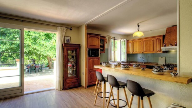 A kitchen with a large island, wooden cabinets, and a view of the outdoors. - Le 55742 - LUCCIANA - Gîte (LUCCIANA)