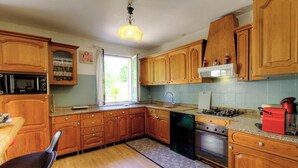 A kitchen with wooden cabinets, a dishwasher, a stove, and a window. - Le 55742 - LUCCIANA - Gîte (LUCCIANA)