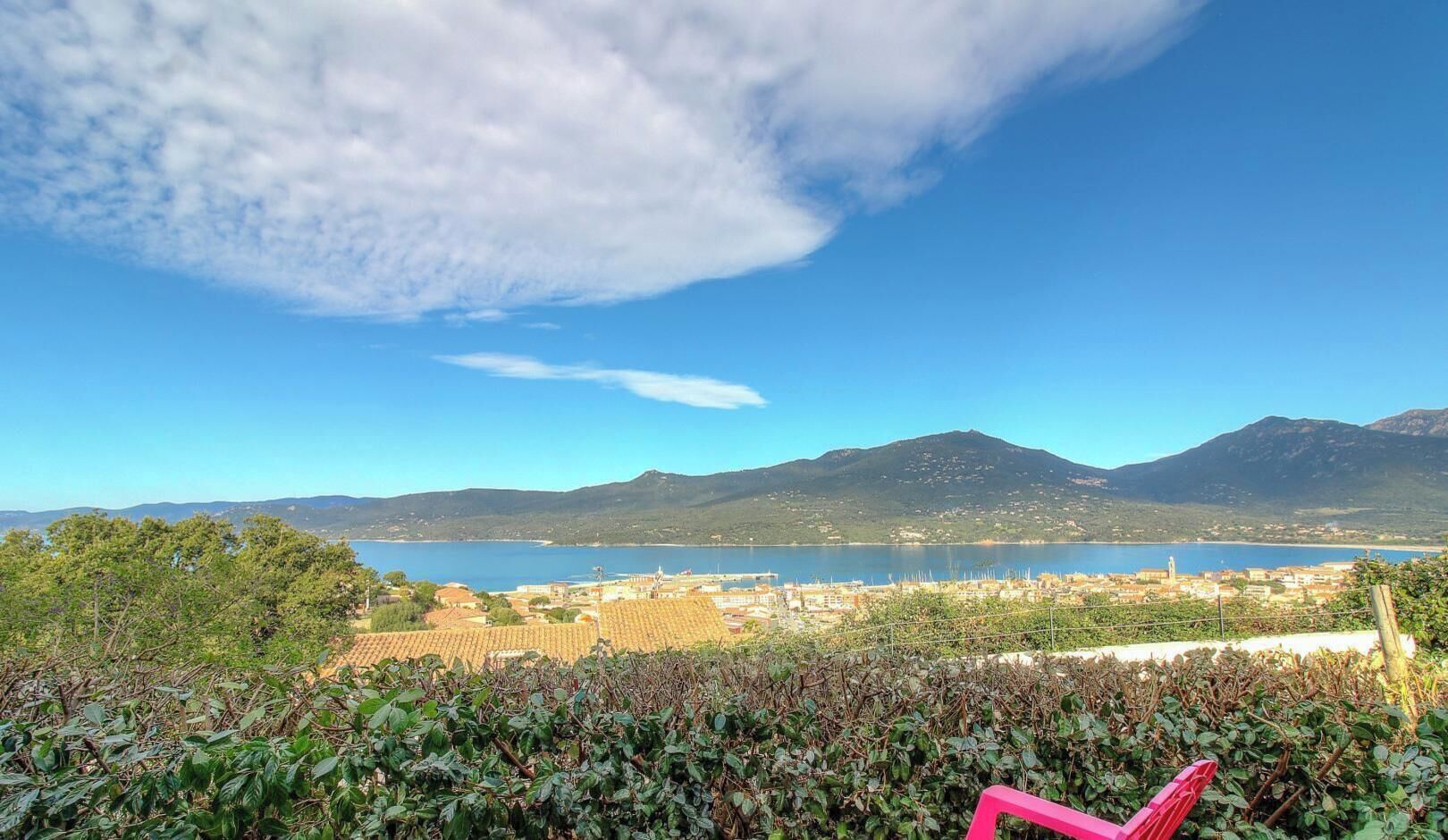 A coastal town with a mountain in the background, a clear sky, and a body of water.