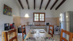 A kitchen with a dining table set for four, a washing machine, and a refrigerator. - I caseddu d'Ulmetu1 - OLMETO (OLMETO)