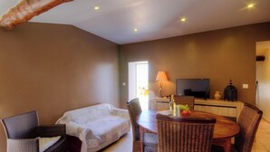 Una habitación con sofá, sillas, una mesa de comedor, televisor y lámpara.