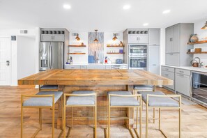 Uma cozinha moderna com uma ilha central de madeira, eletrodomésticos de aço inoxidável e armários em tons claros.