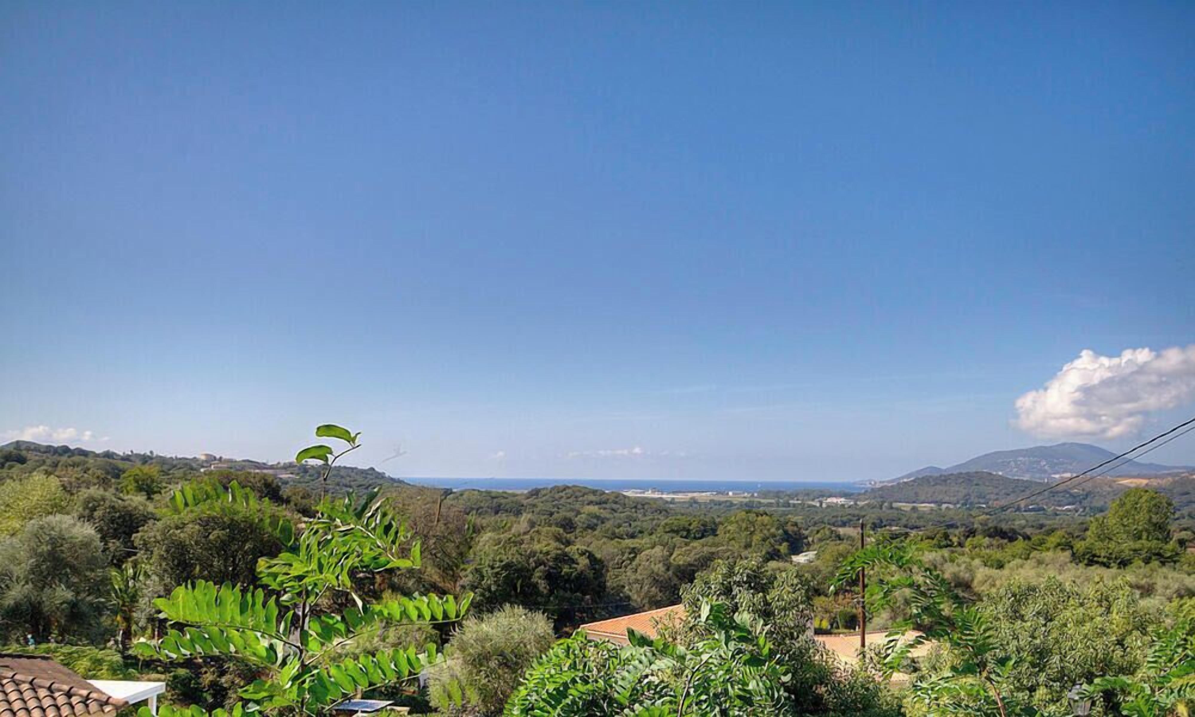 A landscape view with trees, a clear sky, and distant hills.