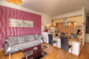 Ein kompakter Wohnbereich mit Sofa, Essplatz und Küchenzeile.