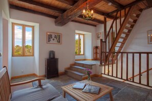 A spacious living area with a wooden staircase, a chandelier, and a view of the outdoors. - Le 59212 - CAMPILE - Gîte (CAMPILE)
