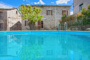 A clear swimming pool with stone buildings in the background. - Le 59212 - CAMPILE - Gîte (CAMPILE)