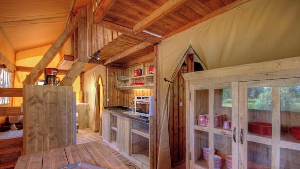 Un interior rústico de madera con una zona de cocina, armarios de madera y una mesa de comedor.