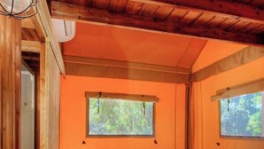 Un dormitorio de cabaña de madera con una cama, una mesita de noche, una lámpara y una ventana.