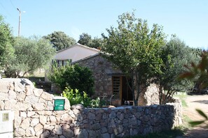 A stone house with a wooden door, a small garden, and a stone wall. - Le Lilas - SOTTA - Gîte (SOTTA)