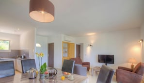 A modern living room with a dining area, a TV, and a kitchen in the background. - A Murta - SOLLACARO - Gîte (SOLLACARO)