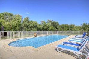 A rectangular swimming pool with a white fence, surrounded by trees and blue lounge chairs. - A TORRA - FARINOLE - Gîte (FARINOLE)