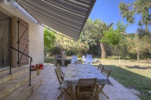 A covered patio with a dining table, chairs, and a grill. - A TORRA - FARINOLE - Gîte (FARINOLE)