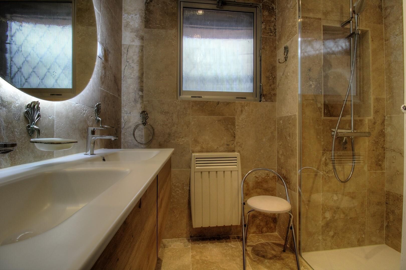 A bathroom with a bathtub, a shower, a toilet, and a window with blinds.