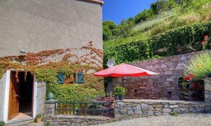 A building with a stone wall, a wooden door, and a red umbrella. - Pian'a le noci - VALLE D'ALESANI (VALLE D'ALESANI)