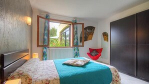 Un dormitorio con cama, ventana con cortinas, ventilador y armario.
