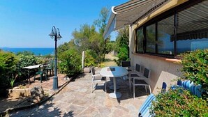 Un patio con mobiliario exterior, un farol y vista al mar.