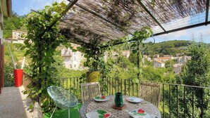 A balcony with a table set for dining, a chair, and a red container. - Casa Cataronu 2 - LEVIE (LEVIE)