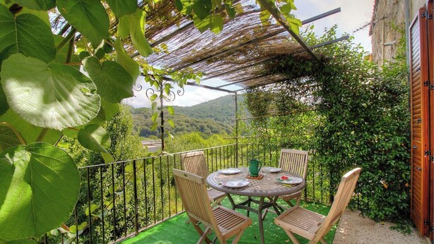 A balcony with a table and chairs, surrounded by greenery and a view of the countryside. - Casa Cataronu 2 - LEVIE (LEVIE)
