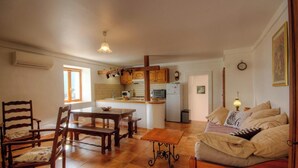 A cozy living room with a sofa, a dining table, and chairs. There is a kitchen area with cabinets and appliances. - U PAGLIAGHJU - CATERI (CATERI)