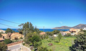 Ein Küstenwohngebiet mit Häusern, Grünflächen und freiem Blick auf das Meer.