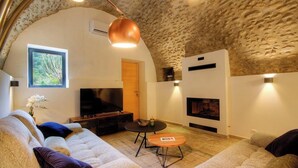A cozy living room with a stone ceiling, a television, a fireplace, and a comfortable sofa. - Casetta Anghjulina - CASTIFAO (CASTIFAO)