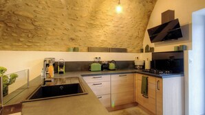A kitchen with a stone ceiling, a sink, a stove, and a green kettle. - Casetta Anghjulina - CASTIFAO (CASTIFAO)