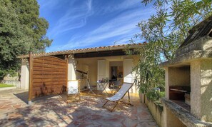 Eine Terrasse mit einem Holztor, einem Tisch mit Stühlen und einem Steinkamin.