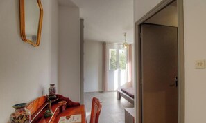Ein Zimmer mit Esstisch, Stühlen, einem Spiegel und einer Tür zu einem anderen Raum.