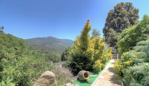 Ein Garten mit einem Pfad, einem großen Felsen und Blick auf die Berge.